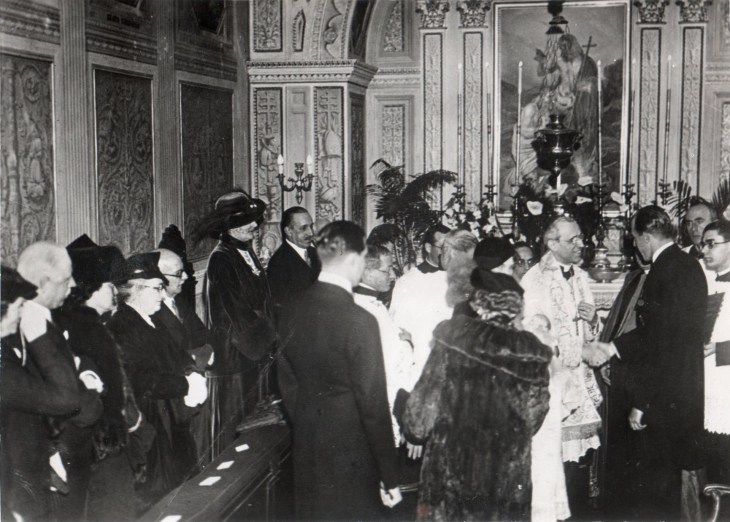 Pie original de la foto: El Cardenal Pachelli - hoy fallecido papa- bautió a S.A.R. Don Juan Carlos. En la foto: la Reina de Italia, Alfonso XIII, el príncipe Chigui -todos fallecidos- y S.M. Dª Victuria Eugenia, madrina con su hijo el Infante don Jaime. S.S. estrecha la mano del Infante D. Jaime